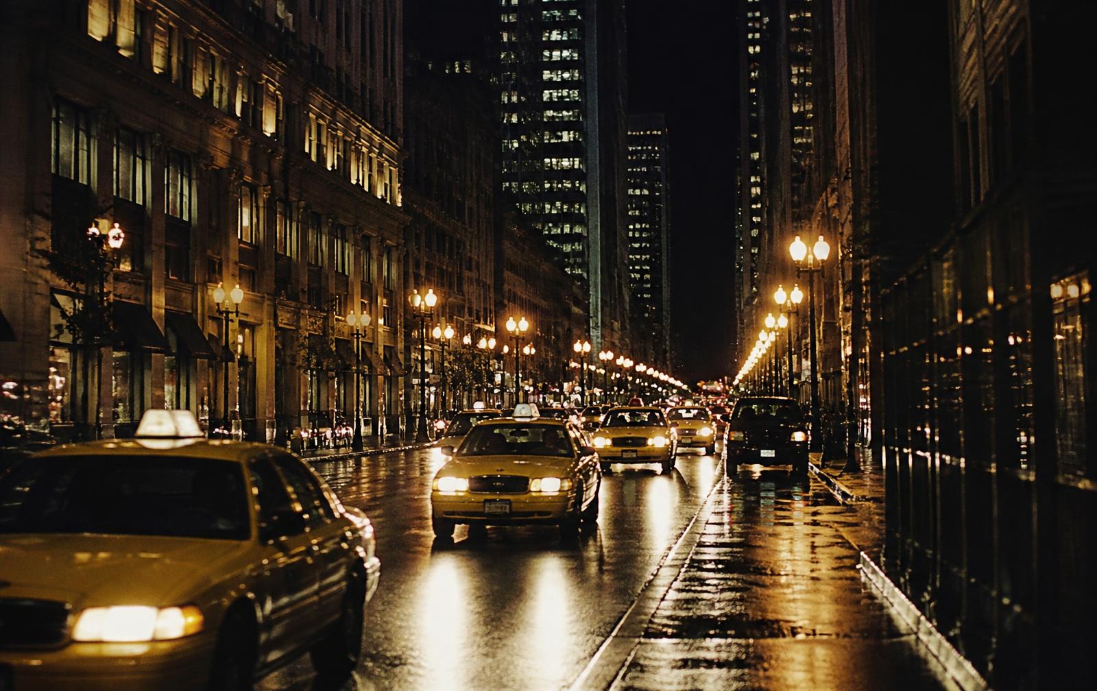 Chicago street at night with taxis and reflections on wet pavement